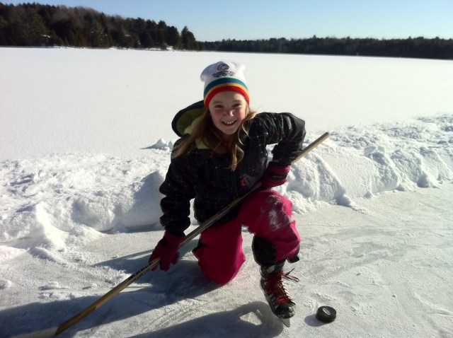 girl with hockey stick on frozen rink