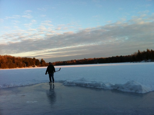 Man standing with hockey stick on a rink on a lake