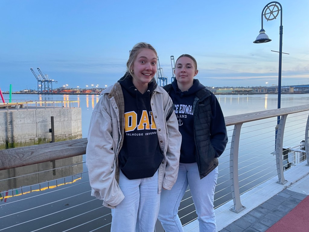 Two teenagers standing on a pier at dusk
